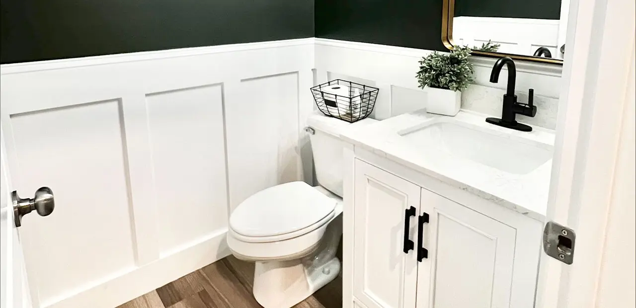 Updated Green Half Bath with White Vanity, Gold Mirror, and Wainscoting