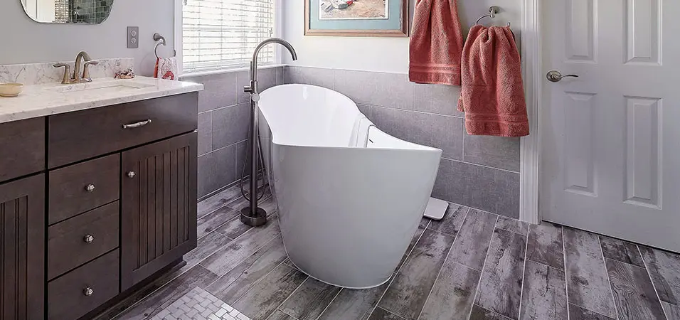 fully remodeled bathroom with gray wooden flooring and dark wood vanity