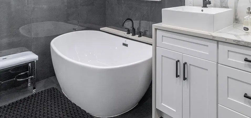 Fully remodeled gray bathroom with standing tub and white vanity